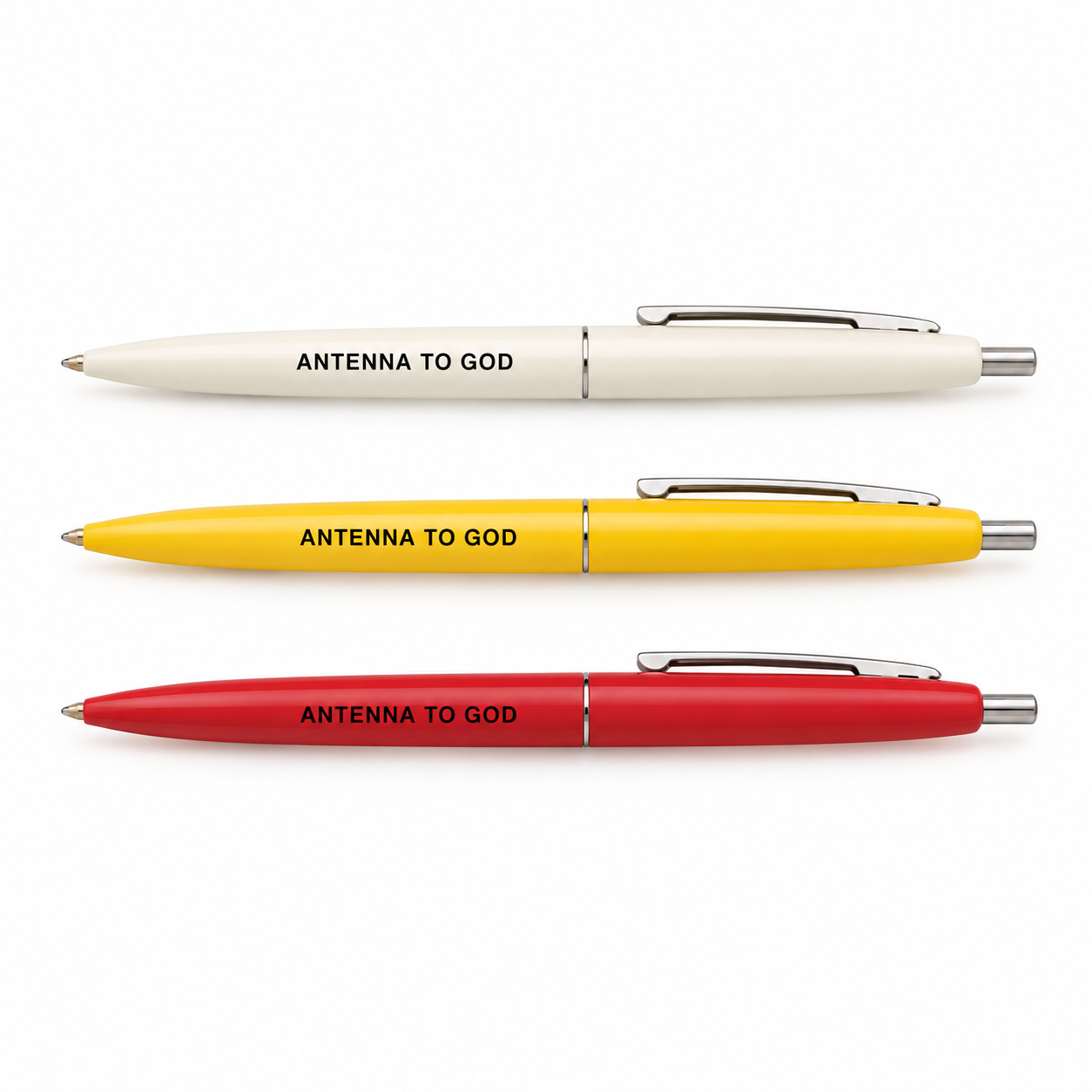 Three Antenna to God click pens in off-white, yellow, and red